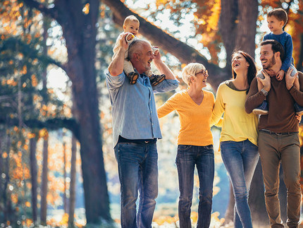 Eine glückliche Familie von drei Generationen steht in einem Park.