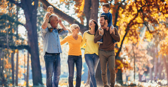 Eine glückliche Familie von drei Generationen steht in einem Park.