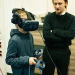 Kind mit VR Brille im Hintergrund ein Erwachsener
