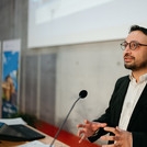 Ein Mann im schwarzen Jacket am Rednerpult