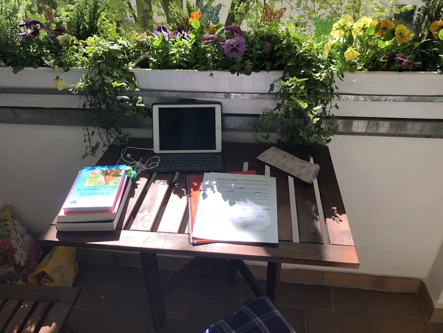 Tisch auf Balkon mit Pflanzen, Büchern und Tablet