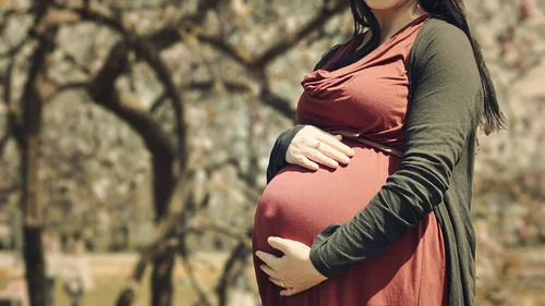 Eine hochschwangere Frau, die ihre Hände auf den Bauch gelegt hat.