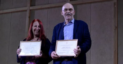 Frank Scherbaum und Caroline Bithell halten die Urkunde der Ehrendoktorwürde in ihren Händen