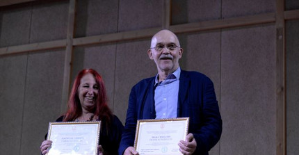 Frank Scherbaum und Caroline Bithell halten die Urkunde der Ehrendoktorwürde in ihren Händen