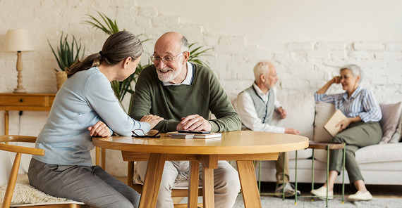 Zwei Personen unterhalten sich an einem Holztisch | Foto: AdobeStock/Comeback Images