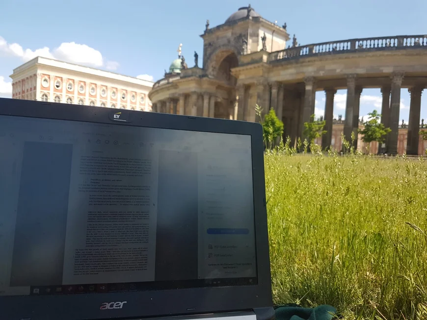 Im Anschnitt der Bildschirm eines Laptops, rechts dahinter die Bauten vom neuen Palais, irgendwas preußisches oder so