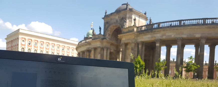 Im Anschnitt der Bildschirm eines Laptops, rechts dahinter die Bauten vom neuen Palais, irgendwas preußisches oder so