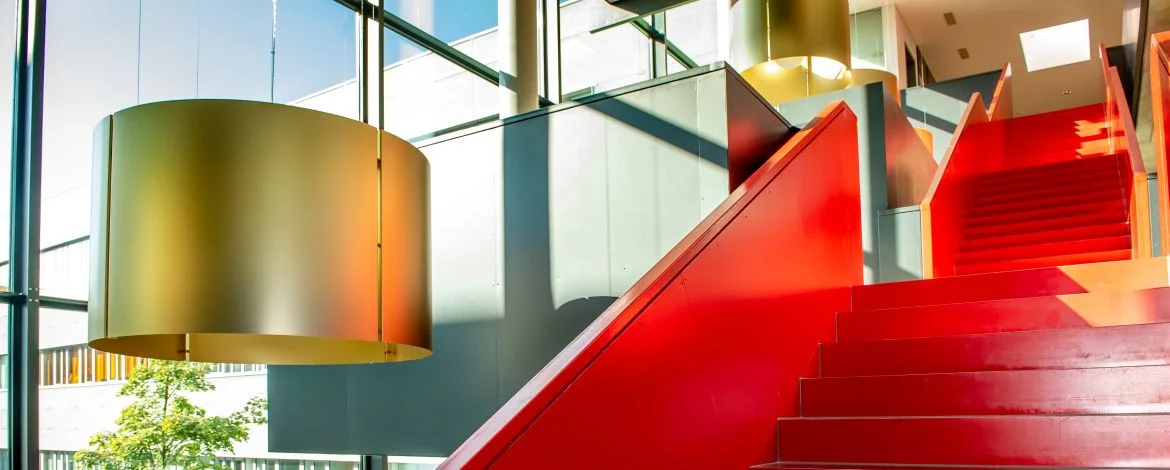 Red staircase in a foyer with a large glass window and a view of the courtyard