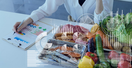 Wissenschaftlerin am Tisch mit vielen Lebensmitteln (Fleisch, Wurst, Fisch, Obst und Gemüse), verschiedene Diagramme über das Bild gelegt