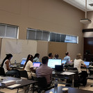 People sitting in a conference room with a large screen in front of them