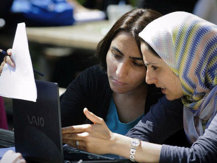 Zwei Frauen sprechen am Computer.
