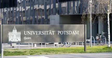 Schild mit Schriftzug „Universität Potsdam“ vor der Fassade eines schwarzen Gebäudes