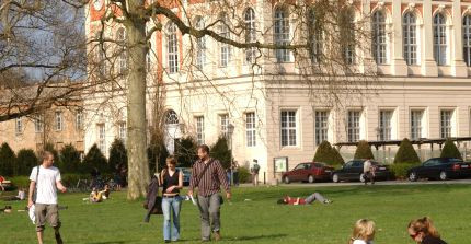 Studierende sitzen in der Pause auf der Wiese.