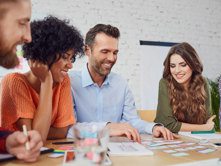 Menschen sitzen um einen Tisch und erarbeiten gemeinsam eine neue Idee.