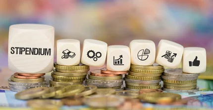 Bild von Geldmünzen und ein Spielwürfel mit dem Wort "Stipendium"