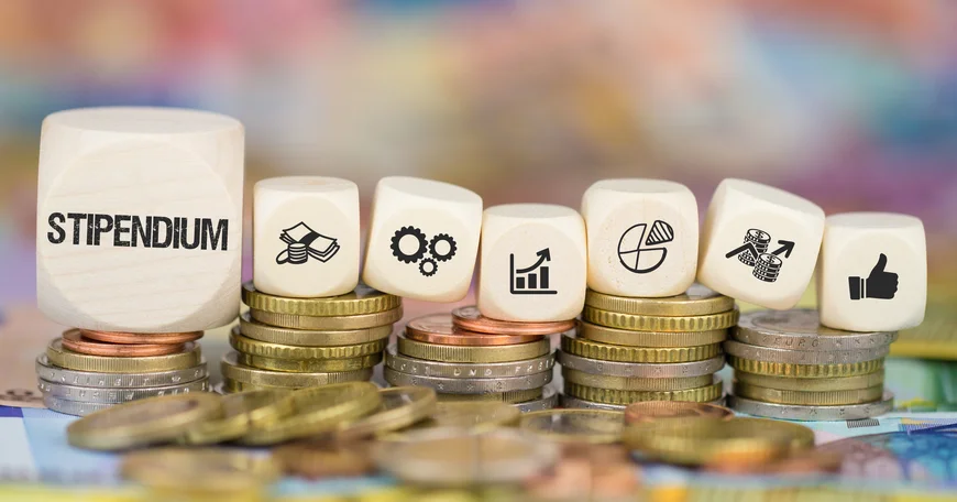 Bild von Geldmünzen und ein Spielwürfel mit dem Wort "Stipendium"