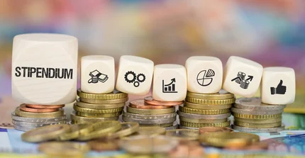 Bild von Geldmünzen und ein Spielwürfel mit dem Wort "Stipendium"