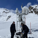 Field site Dresdner Hütte: Two scientists with a mobile CRNS sensor on a sled standing next to measuring devices installed at a alpine hillslope | Photo: Cosmic Sense Consortium