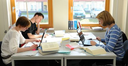 Studierende sitzen an einem Tisch in der Bibliothek