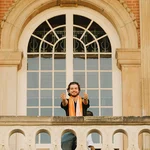 Eine Person posiert vor einem der historischen großen Fenster des Haus 9.