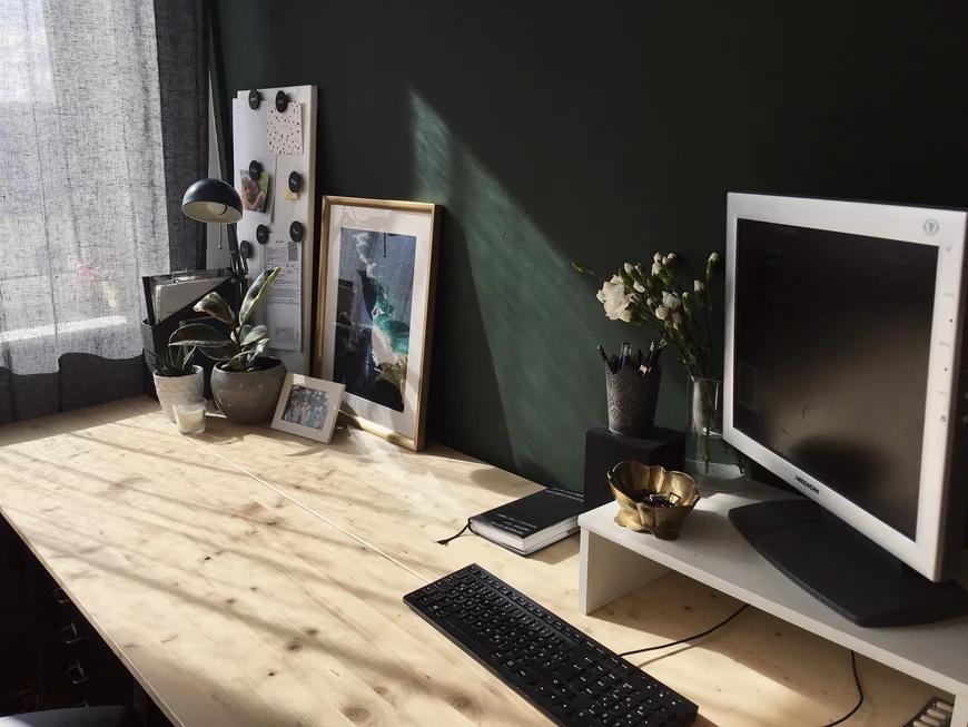 Ein sehr ordentlicher Schreibtisch, das Licht vom Fenster fällt gleichmäßig drauf, es steht eni Laptop da