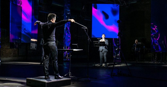 Das Foto zeigt drei Musiker auf der Bühne während eines Konzerts mit einer Visualisierung auf Projektionswänden. Beim anklicken öffnet sich das Bild im neuen Fenster.