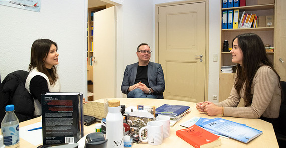 Die beiden Mitarbeiterinnen Catinca Barsan (l). und Jacqueline Banzer (r.) mit Marcus Schladebach (Mitte) am Tisch.