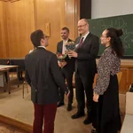 Auf dem Bild sieht man die Gäste der Podiumsdiskussion bei der Blumenstraußübergabe.