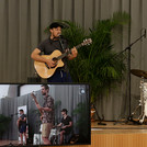 Eine dreiköpfige Band (Schlagzeug, Bass, Gitarre) spielt auf einer kleinen Bühne.