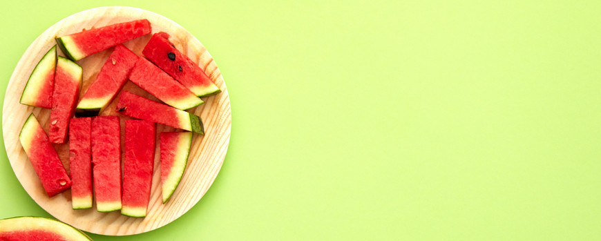 Wassermelonenstücken auf einem Teller vor einem hellgrünen Hintergrund