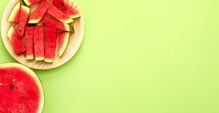 Wassermelonenstücken auf einem Teller vor einem hellgrünen Hintergrund