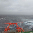 Paula standing on the helideck of the ship watching the stormy sea