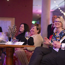 Vier Personen auf Stühlen, die lachen und klatschen.