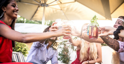 Freunde bei einer Sommerparty stoßen mit einem Getränk an.