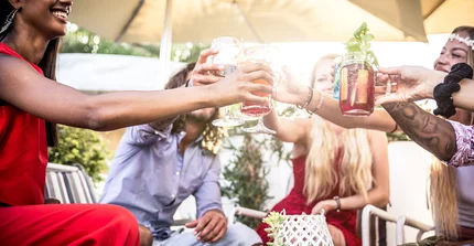 Freunde bei einer Sommerparty stoßen mit einem Getränk an.