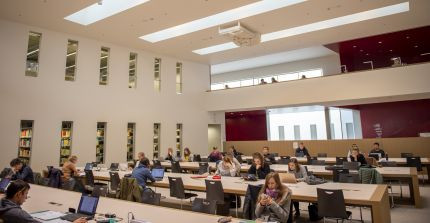 Studierende sitzen an den Arbeitsplätzen in einem großen Lesesaal der Universitätsbibliothek