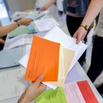 Hände reichen sich gegenseitig Stimmzettel