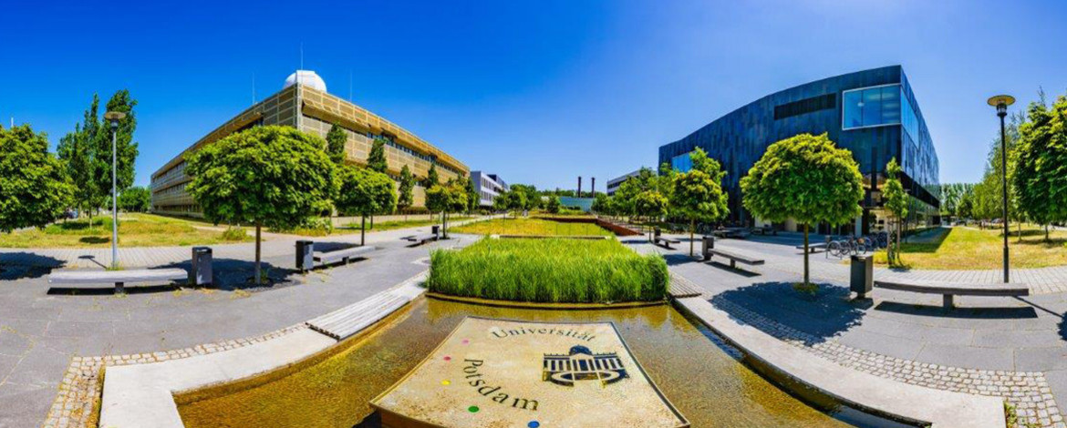 Aufnahme von zwei Gebäuden, in der Mitte ein Wasserspiel - 