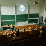 Blick auf einen Hörsaal mit grüner Tafel und der Projektion der Erde an der Leinwand