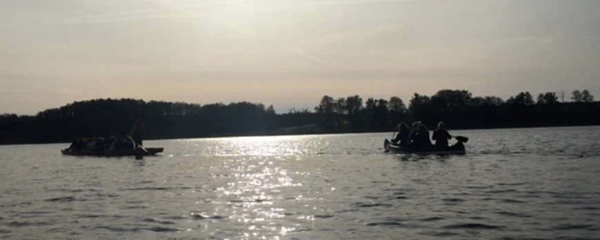 2 Kanus fahren auf einem See vor untergehender Sonne