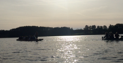 2 Kanus fahren auf einem See vor untergehender Sonne