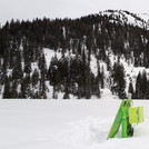 Field site Esterberg: A bright green CRNS sensor with solar panel standing on a white plain with black and white forested mountains in the background | Photo: Cosmic Sense Consortium