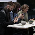 Drei Studierende formen Schweinchen aus Ton bei der Ausstellung des Fachbereichs Kunst.
