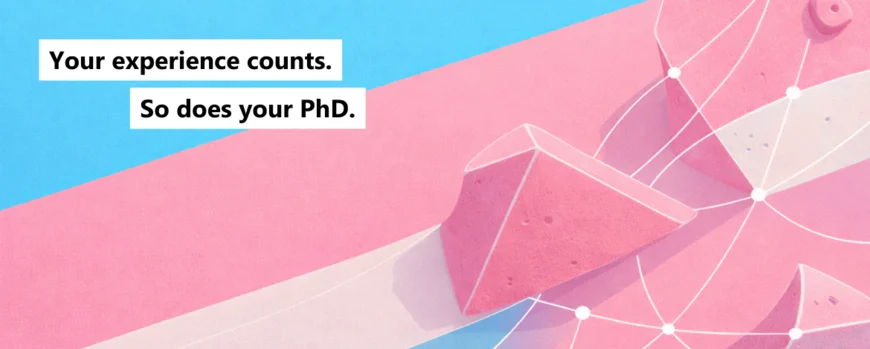 A bouldering wall in the in turquoise and pink with the slogan “Your experience counts. So does your PhD.".”