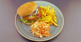 Planted-Chicken-Burger auf einem Teller mit Pommes und Krautsalat.