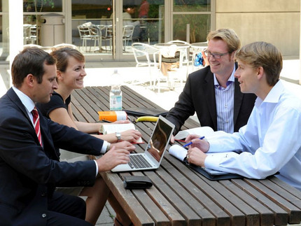 Vier Hochschul-Mitglieder sitzen an einem Tisch um einen Computer. Im Internet stehen viele Angebote der Universität. Foto: Karla Fritze