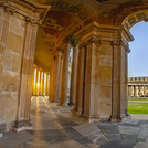 Blick aus einem halbrunden Säulengang auf ein historisches Nebengebäude des Neuen Palais