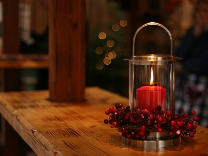 rote Kerze von Beeren umgeben auf einem Tisch