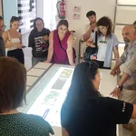 Teilnehmende der Exkursion stehen um einen Lichttisch herum. Eine Frau erklärt.