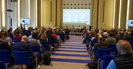 Paneldiskussion mit Publikum. Blick aus dem Publikum auf die Bühne.